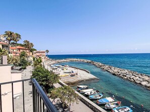 Un poble costaner amb un port esportiu, edificis i un cel blau clar.