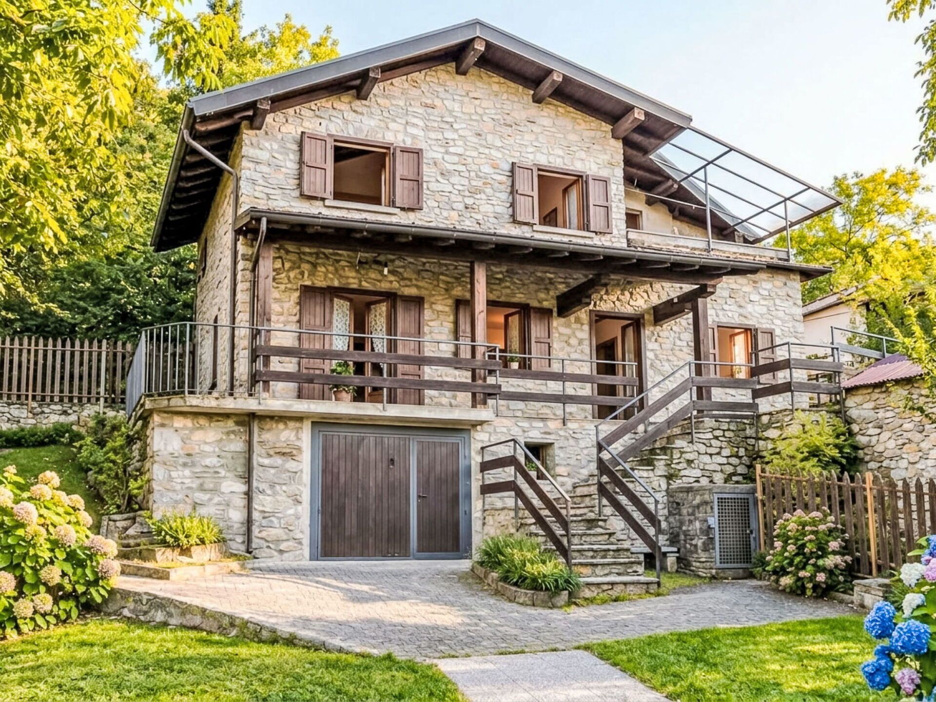 A two-story stone house with a wooden balcony and a staircase leading to the upper floor.