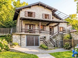 Ein zweistöckiges Steinhaus mit einem Holzbalkon und einer Treppe, die zu der oberen Etage führt.