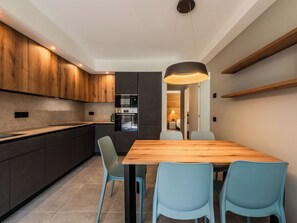 Eine moderne Küche mit dunklen Schränken, einem Holztisch und hellblauen Stühlen.