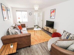 A modern living room with a sofa set, a TV, and a small table with a plant. - 5 Warrington Lane (Coventry)