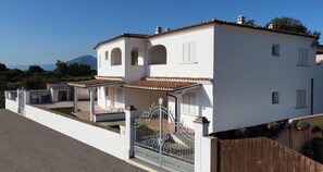Un bâtiment à deux étages, doté d’une façade blanche, d’une entrée fermée par un portail et offrant une vue dégagée sur le paysage environnant.