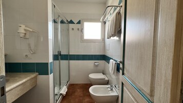 Un baño con cabina de ducha de vidrio, inodoro y lavabo.