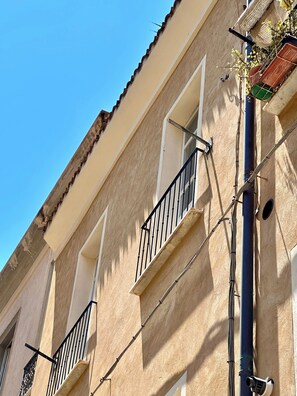 A building facade with multiple balconies, a window, and a visible pipe. - Charming 2-bedroom apartment in the heart of the historic center (Cagliari)