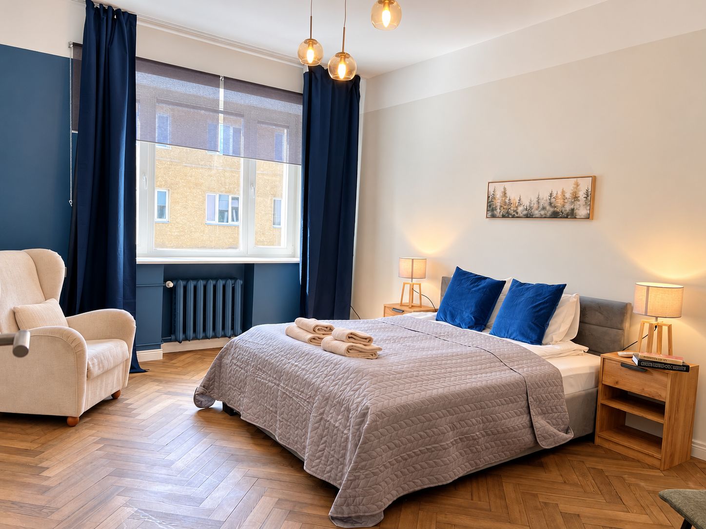 A hotel room with a bed, a chair, a bedside table, a lamp, and a window with curtains.