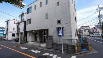 A multi-story building with a gated entrance, a blue sign, and a street with marked lanes.
