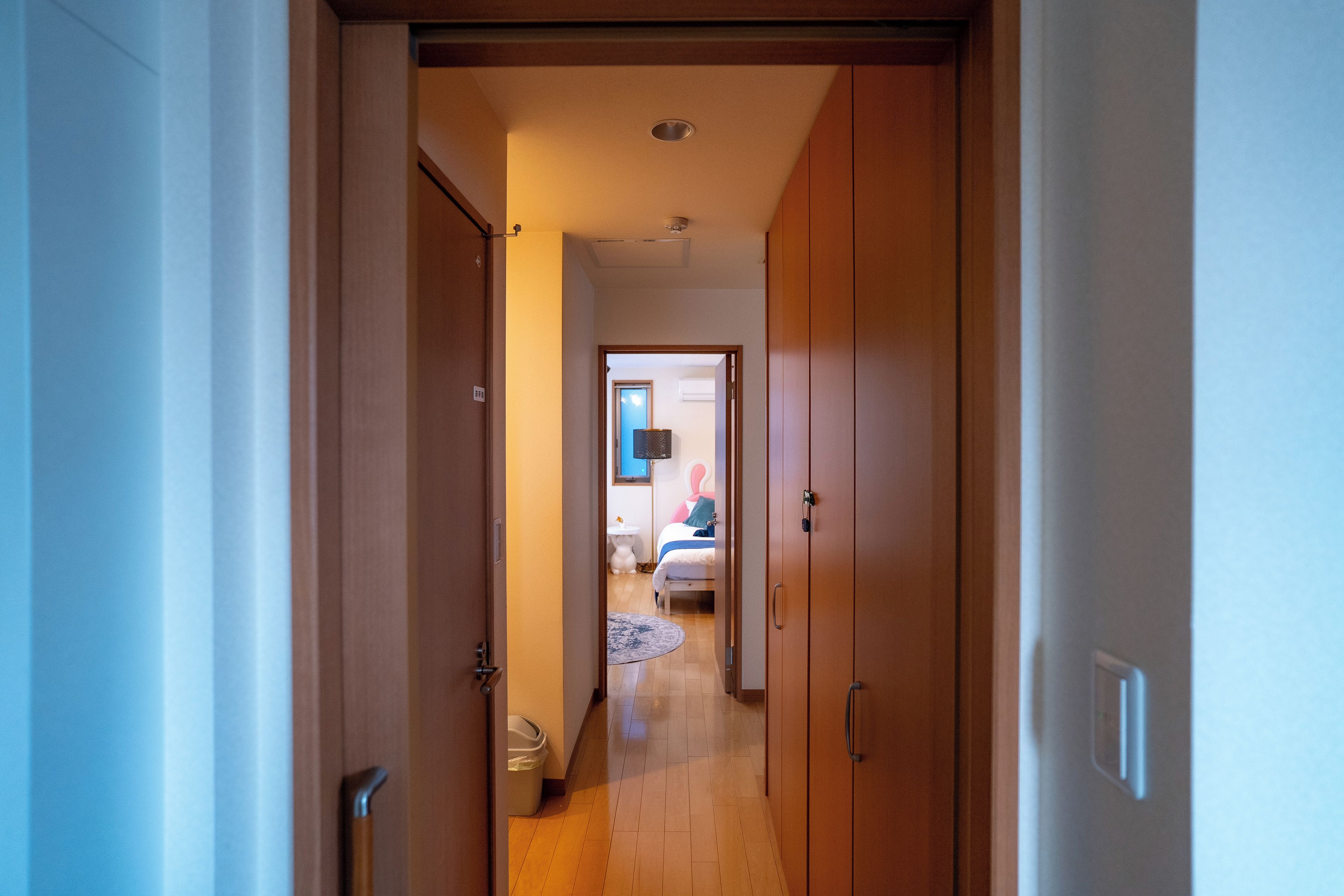 A hallway leading to a bedroom with a bed, a bedside table, and a wardrobe.