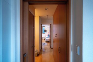 Un pasillo que conduce a un dormitorio con una cama, una mesita de noche y un armario.