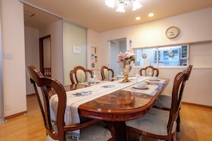 A dining room with a wooden table set for six, surrounded by six chairs. - Rabbit house (Edogawaku)