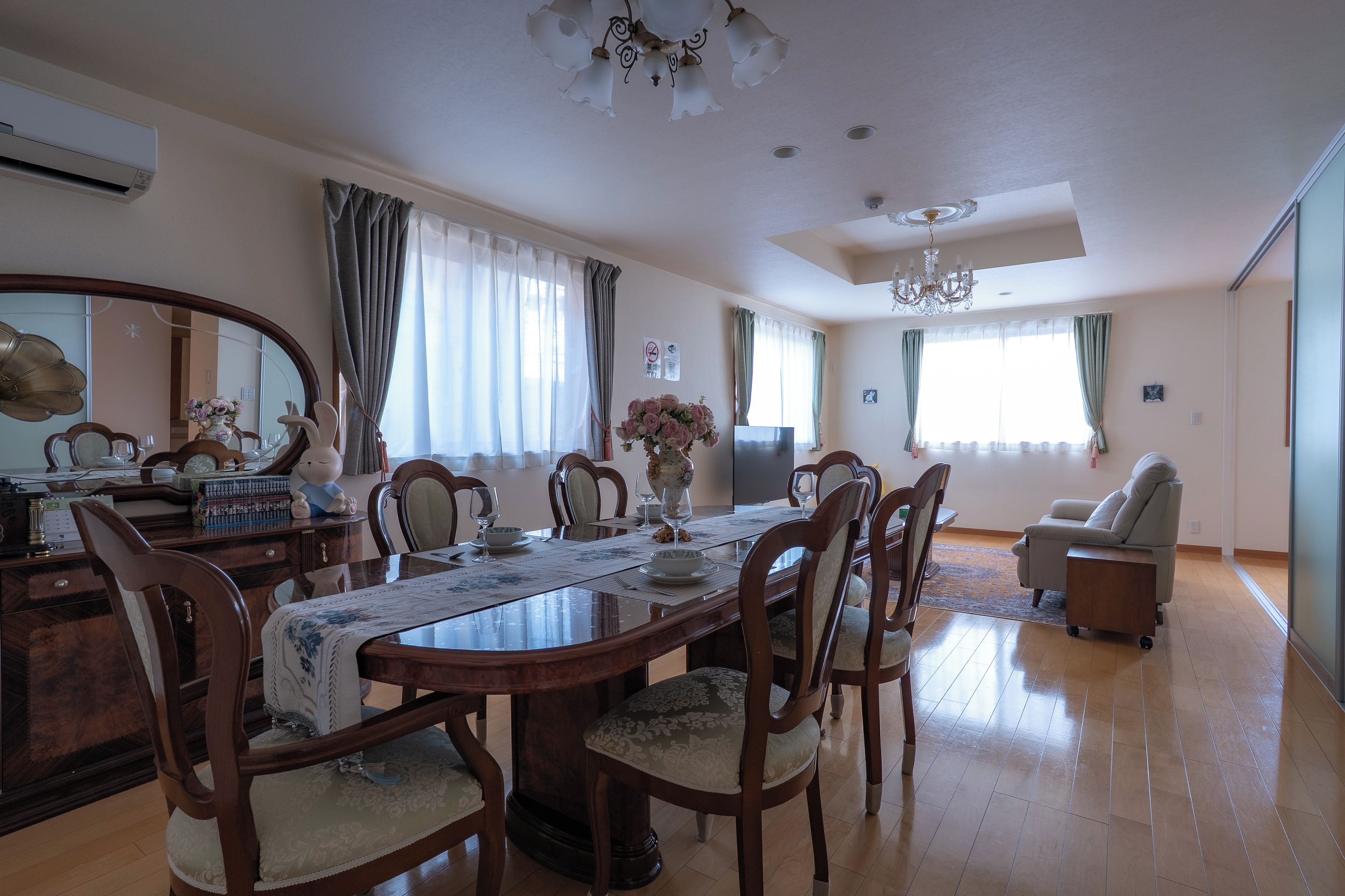 A dining room with a wooden table set for four, surrounded by chairs.