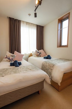 A hotel room with two beds, a window, and a ceiling light. - Rabbit house (Edogawaku)
