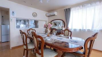 A dining area with a wooden table, chairs, a clock, and a window with curtains.