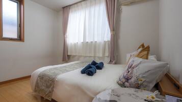 A bedroom with a bed, a window, and a curtain.