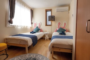 A hotel room with two beds, a window with curtains, an air conditioning unit, and a small round table. - Rabbit house (Edogawaku)