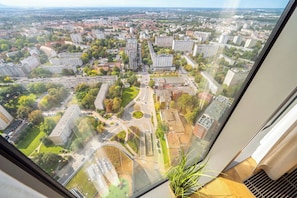 Ein Hochhaus mit Blick auf eine Stadtlandschaft, darunter Straßen, Gebäude und Grünflächen.