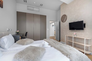 A modern bedroom with a bed, a TV mounted on the wall, and a wardrobe. - Wroclaw | Gwiaździsta 64 | Apartment with a View | Parking (Wrocław)