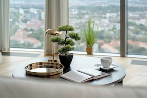 A room with a view of a cityscape, a bonsai tree, a lamp, a cup, and a book on a table. - Wroclaw | Gwiaździsta 64 | Apartment with a View | Parking (Wrocław)