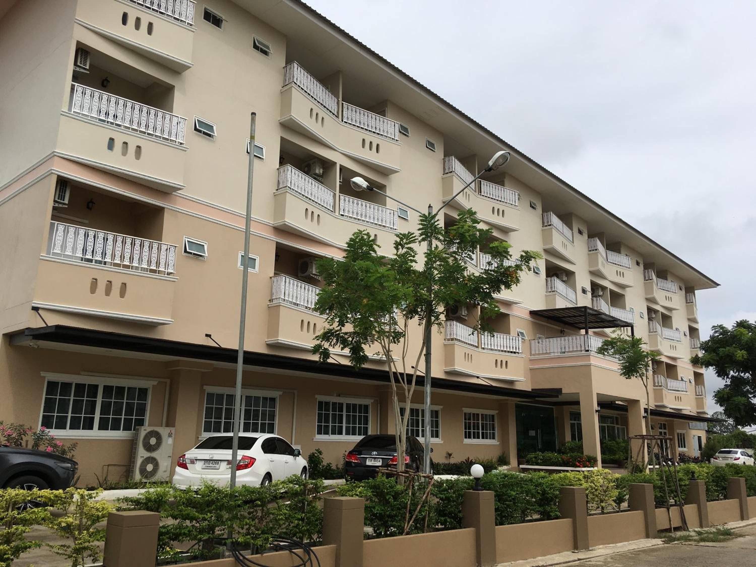 A multi-story residential building with balconies, air conditioning units, and parked cars.