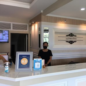 A hotel reception desk with a framed award, a digital screen, and a sign with the hotel name. - Boonbundal Hotel (Roi Et)