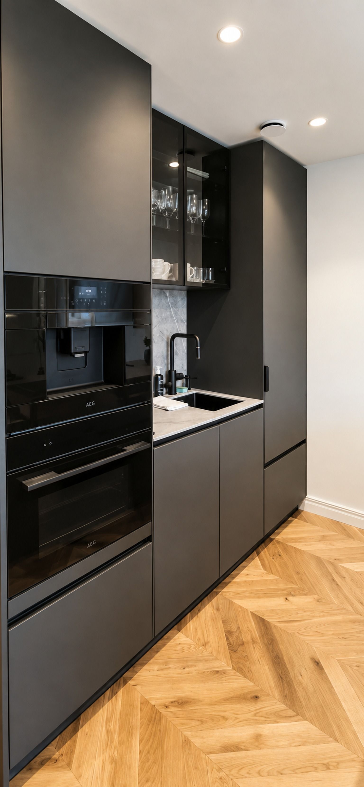 Una cocina moderna con electrodomésticos integrados, un fregadero y un piso de madera en espiga.