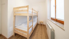 Een slaapkamer met een stapelbed, een tafeltje en een raam.