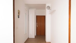 Ein Flur mit einer Holztür am Ende, einem Lichtschalter und einer Wandleuchte.
