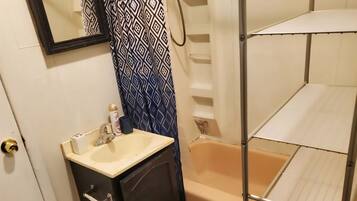 A bathroom with a sink, mirror, toilet, and bathtub.