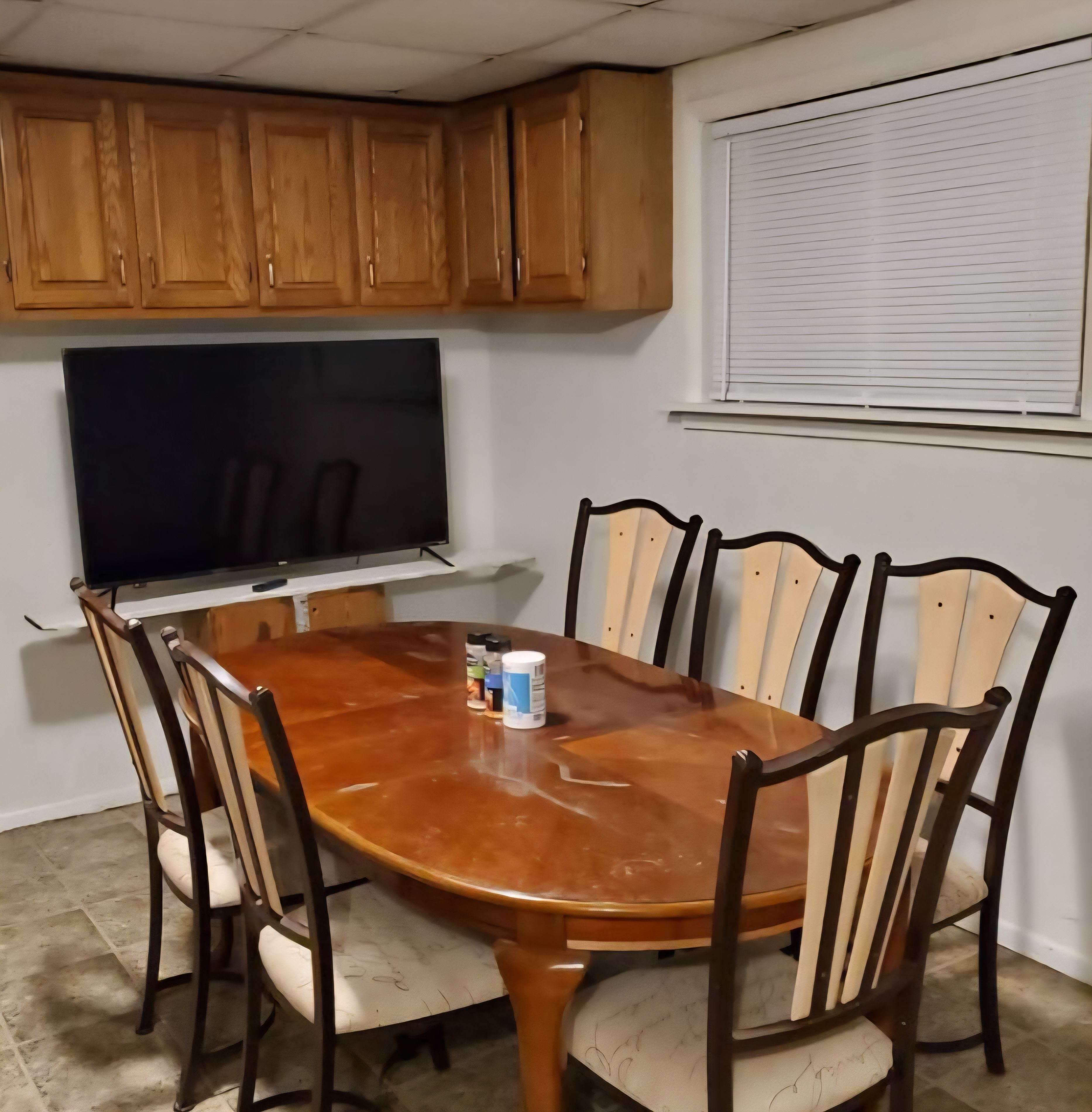 A dining area with a wooden table, six chairs, a television, and wooden cabinets.