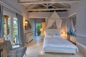 A bedroom with a canopy bed, a desk, a chair, and a view of the outdoors. - Anerada Inn Suites Pool & Spa | Blue Suite (Megalo chorio)