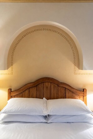 Un lit avec une tête de lit en bois et un arc décoratif au-dessus.