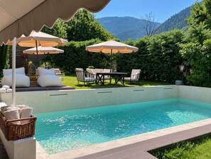 A swimming pool with a view of a mountainous landscape, surrounded by outdoor furniture and umbrellas. - Anerada Inn Suites Pool & Spa | Master Suite (Megalo chorio)