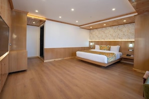 Una habitación de hotel moderna con una cama grande, suelo de madera y armarios empotrados.