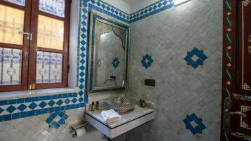 A bathroom with a sink, mirror, and decorative tiles.