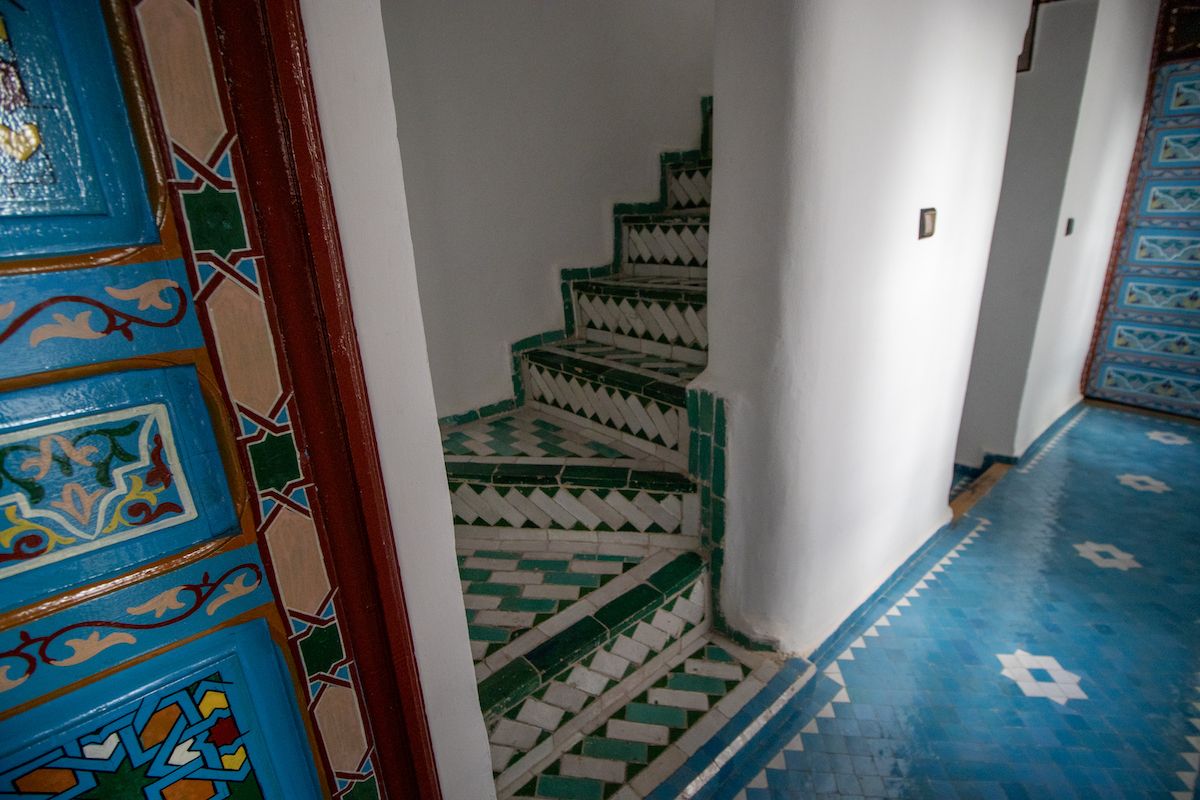 Un escalier dont le sol et les murs sont ornés de motifs géométriques, menant à un niveau supérieur.