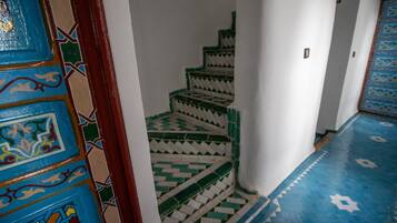 Un escalier dont le sol et les murs sont ornés de motifs géométriques, menant à un niveau supérieur.
