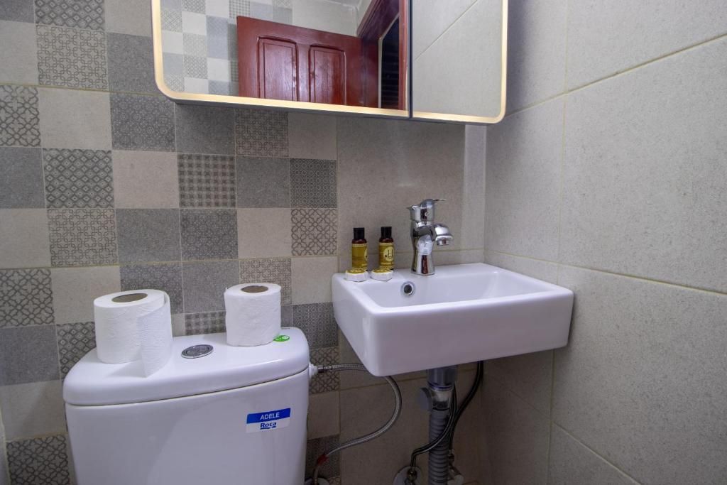 Une salle de bain avec des toilettes, un lavabo et un miroir.