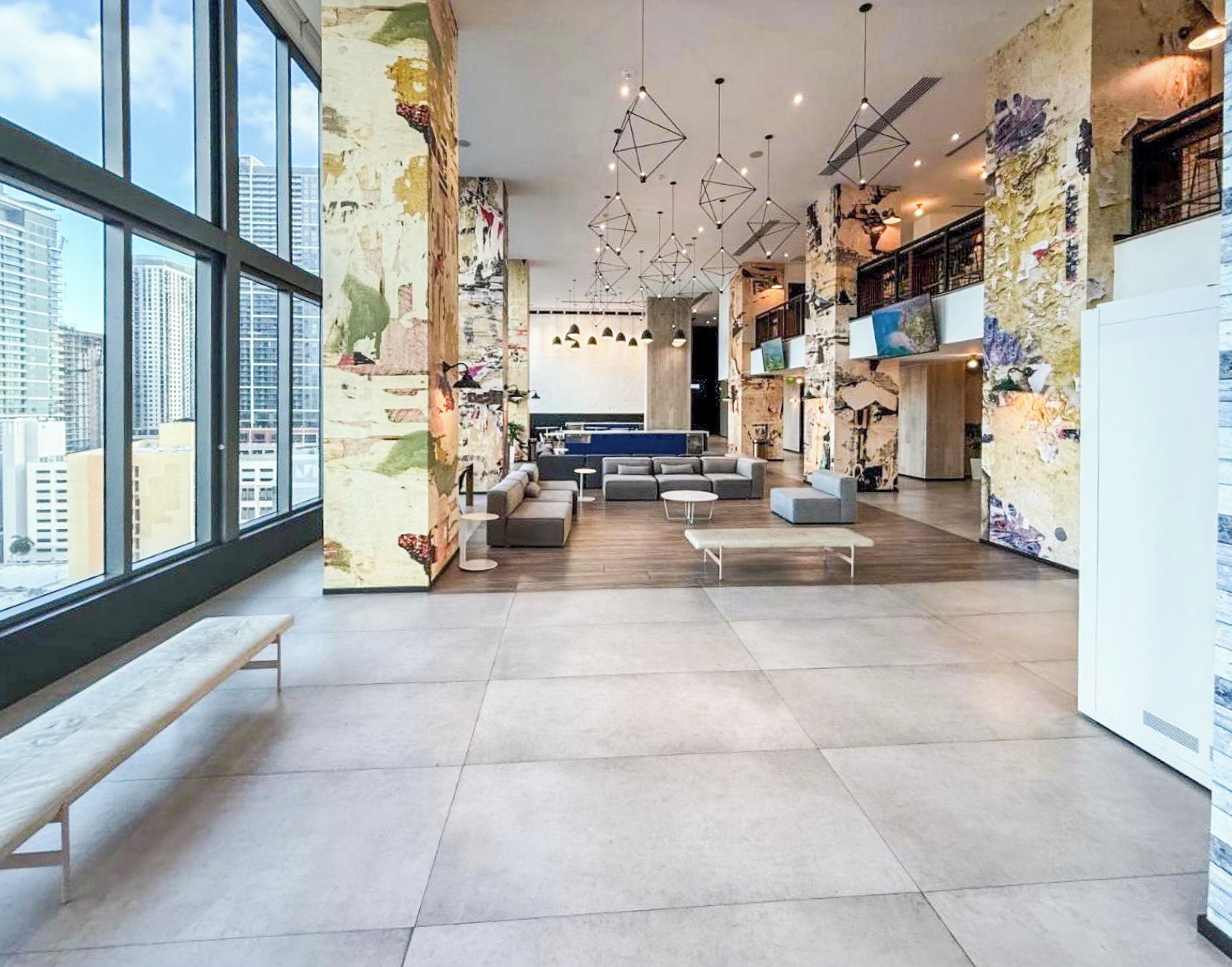 A spacious lobby with a pool table, seating area, and large windows offering a city view.