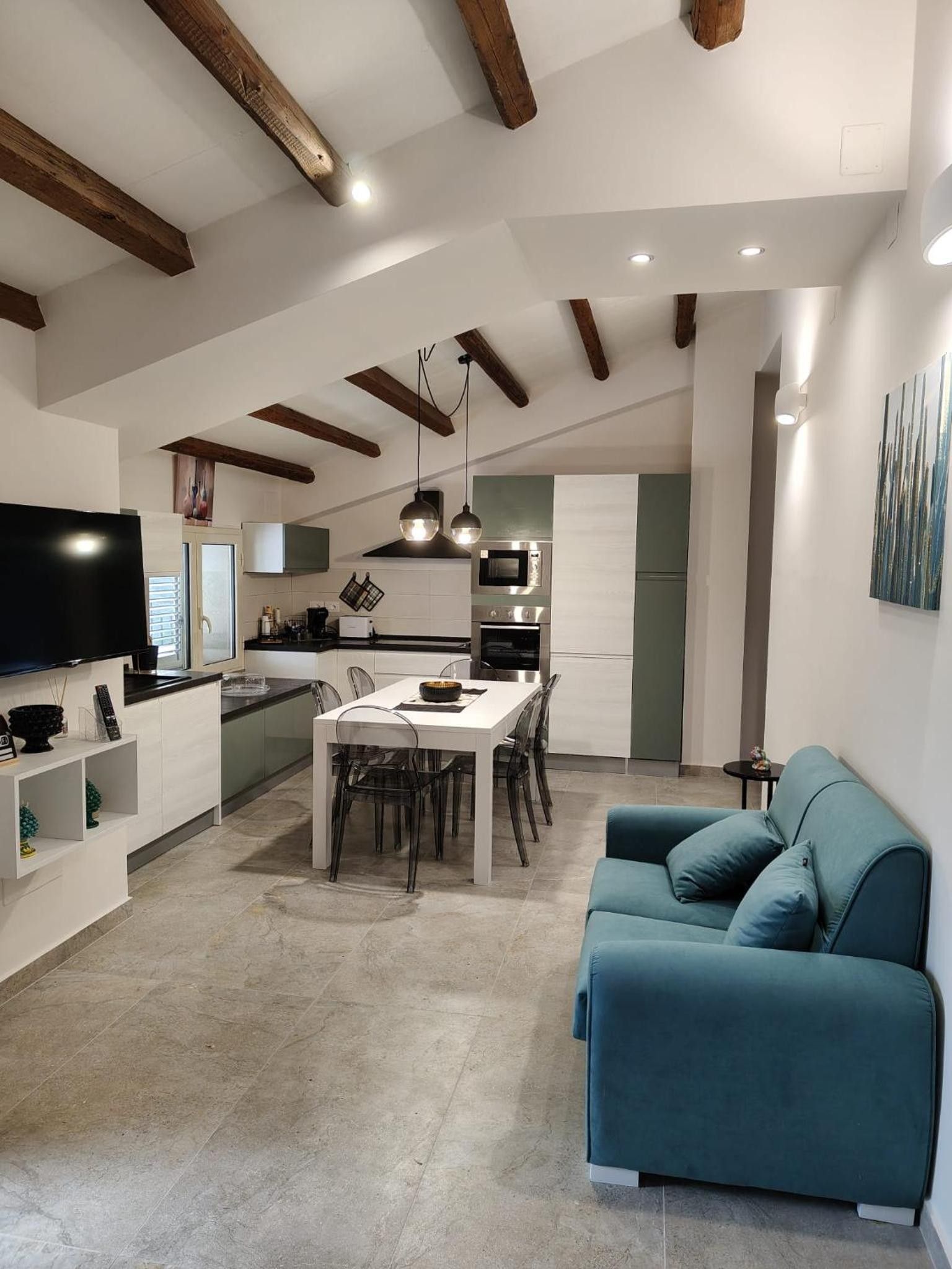 Cuina moderna amb zona de menjador, televisió de pantalla plana i sofà color aquamarina.