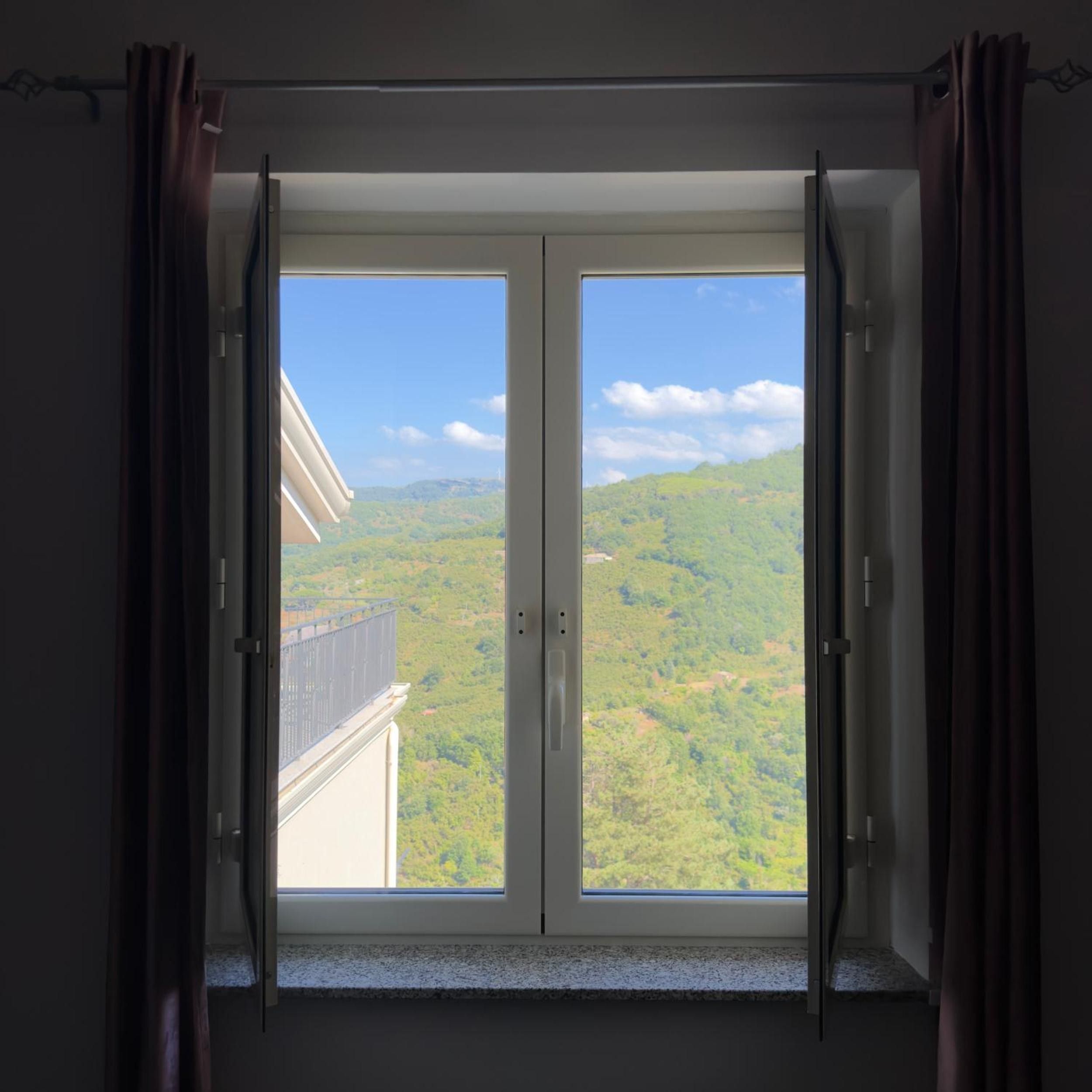 Ein Zimmer mit einer großen Schiebetür, die auf einen Balkon mit Blick auf eine grüne Landschaft führt.