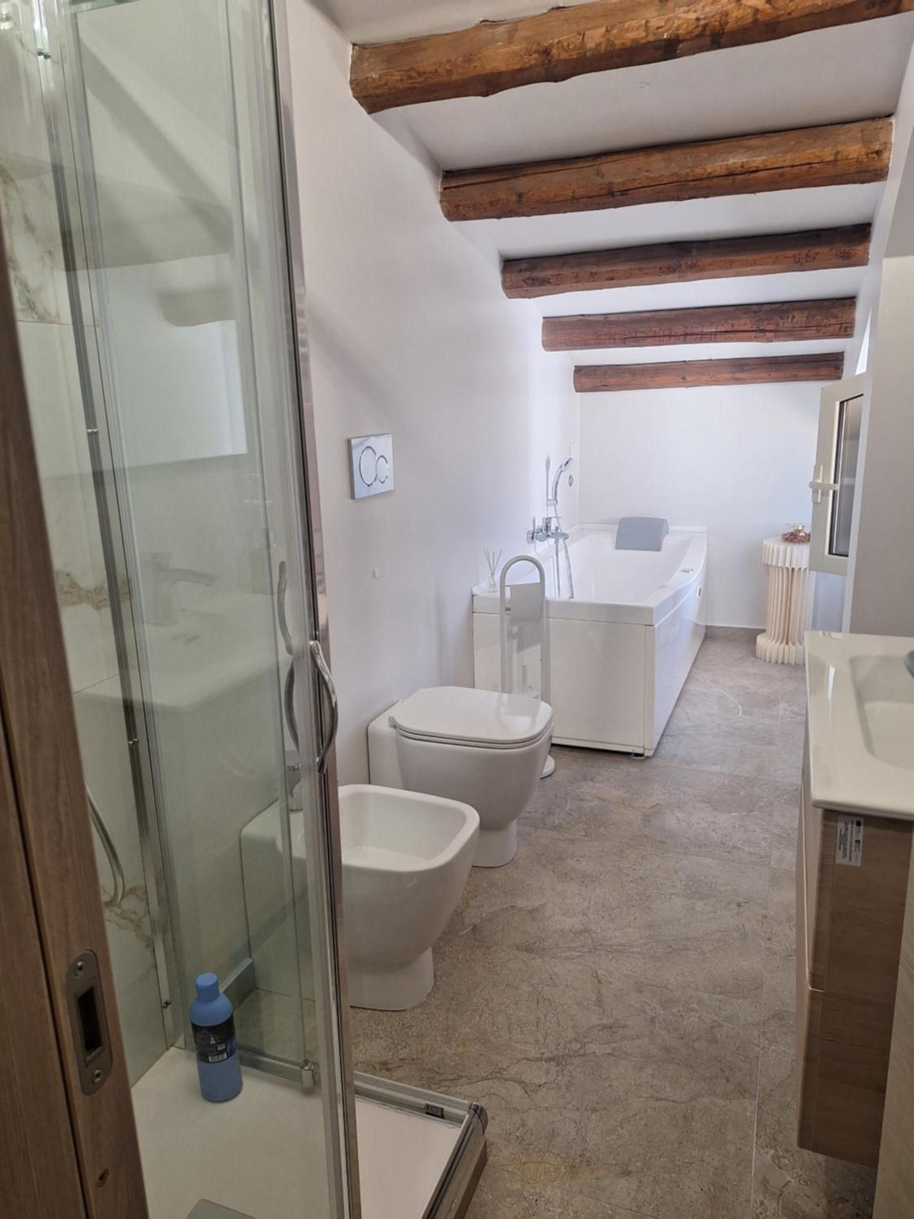 Un bany amb un plat de dutxa de vidre, dues vàteres, una banyera i un lavabo.