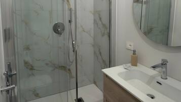 Une salle de bain moderne avec une douche à parois de verre, des toilettes blanches et un meuble-lavabo en bois avec un évier.