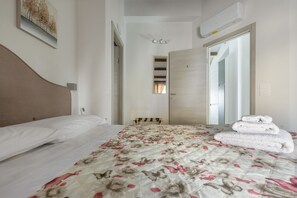 A hotel room with a bed, a bedside table, a mirror, a wardrobe, and a bathroom door.
