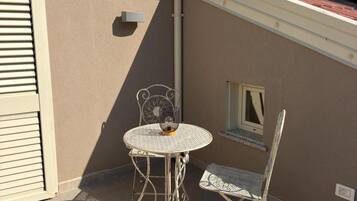 Un patio con una mesa redonda y dos sillas, una ventana pequeña y un panel solar en el techo.