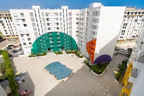 Un edifici residencial de diverses plantes amb balcons, un pati central amb piscina i una zona d'aparcament.