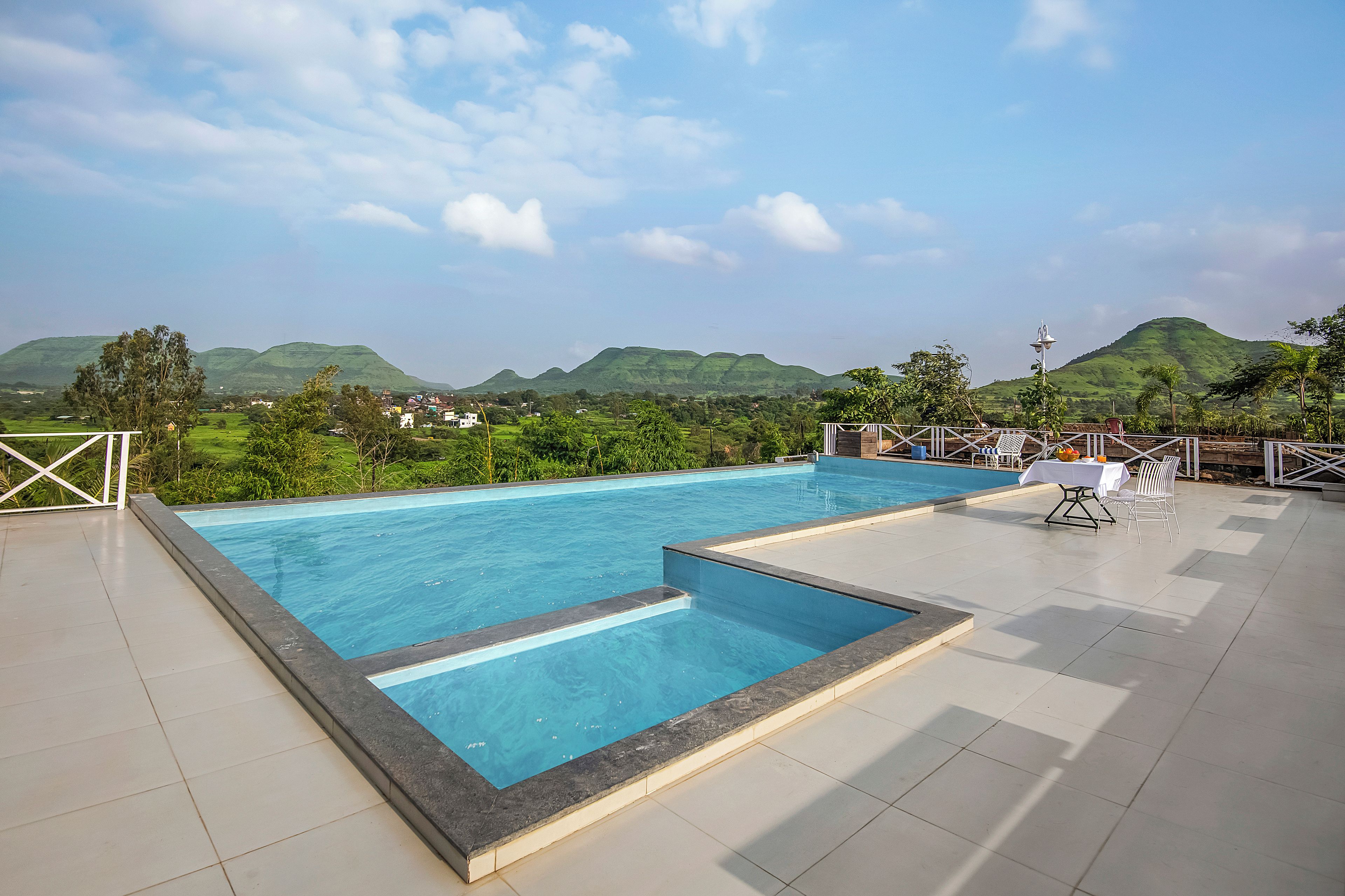 Una piscina con vistas a colinas verdes al fondo.