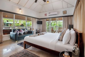 A spacious bedroom with a large bed, a sofa, and a TV.