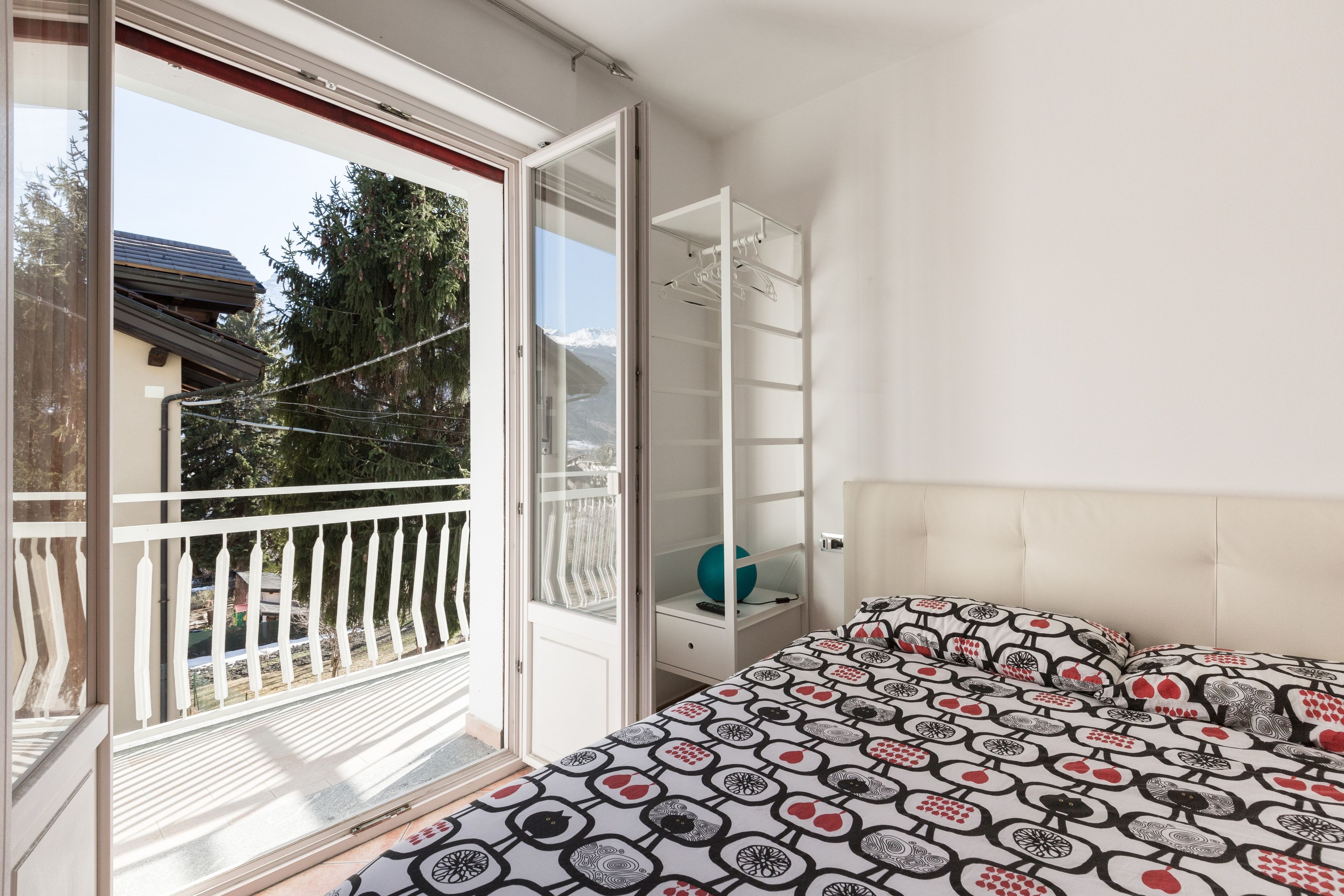 A bedroom with a bed, a wardrobe, and a balcony.