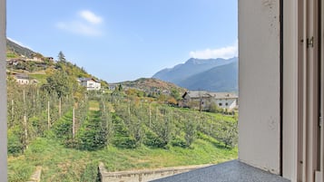 Un balcón con vistas a un pueblo en la ladera, casas y montañas.