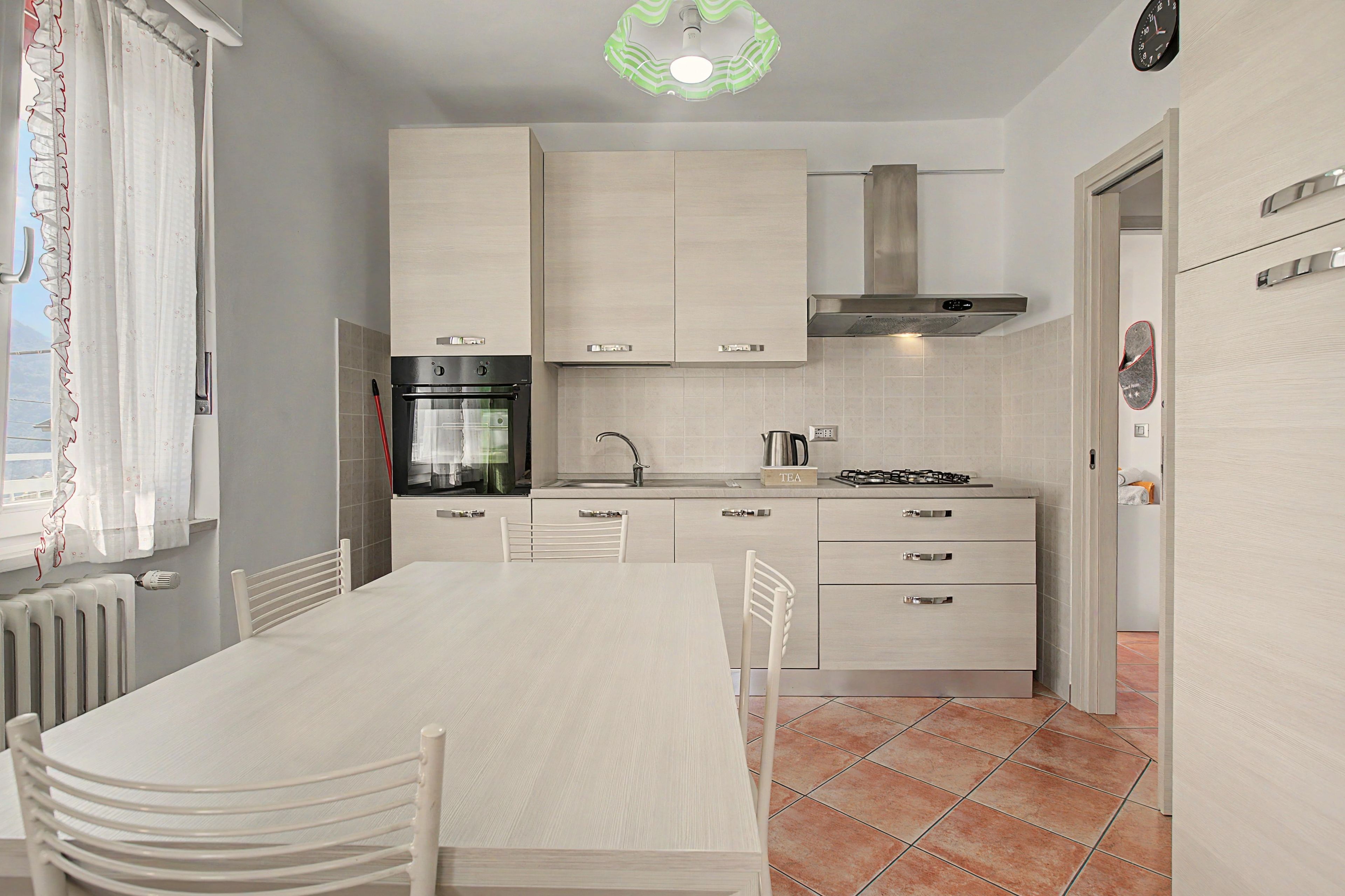 Une cuisine moderne équipée d’une table à manger, de chaises, d’une cuisinière et d’un four encastré.