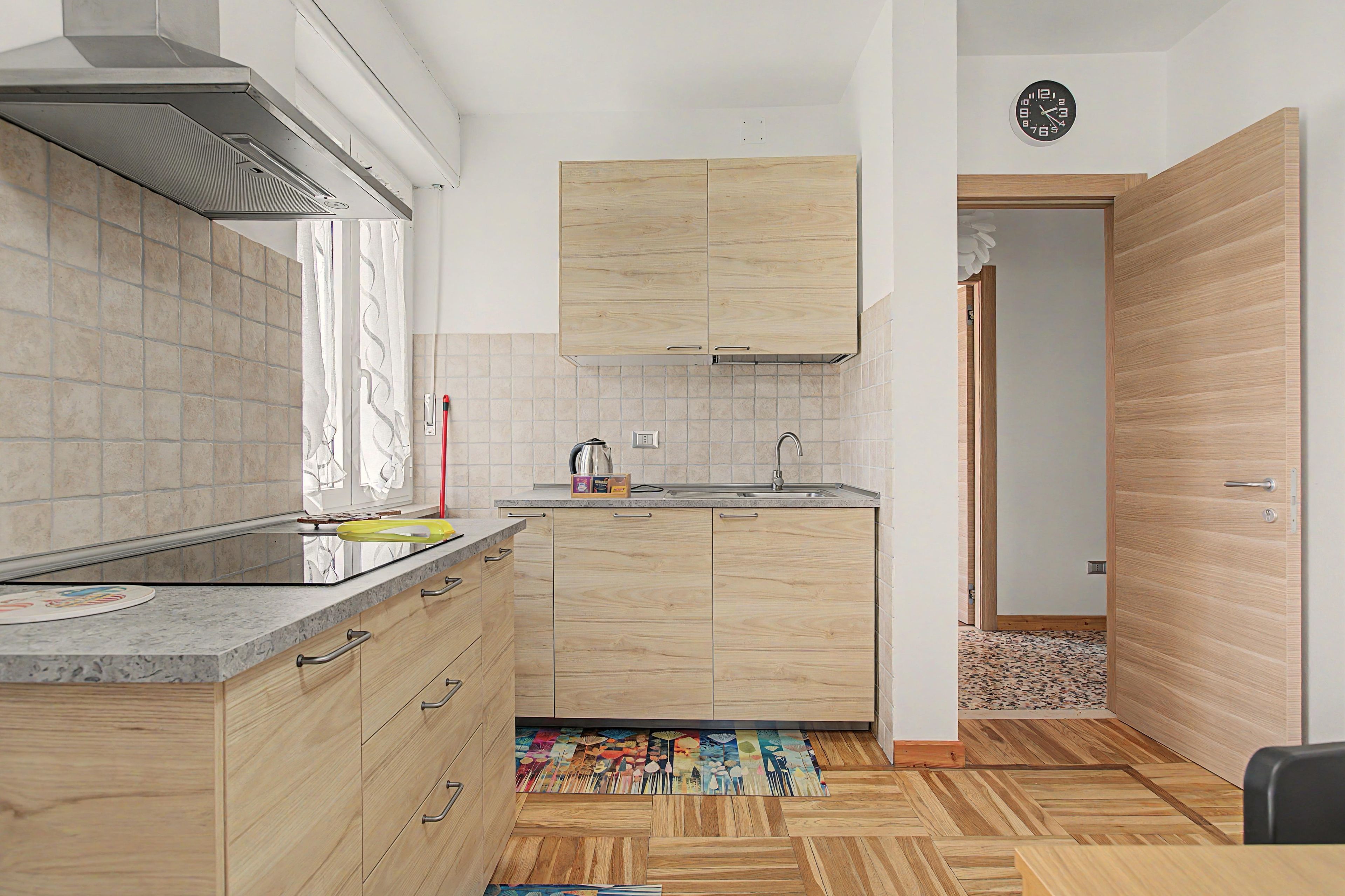 Une cuisine moderne avec des meubles en bois, un évier en acier inoxydable et un dosseret carrelé.